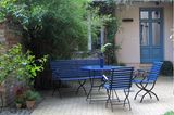 Blau lackierte Gartenmöbelsitzgruppe in einem Innenhof mit begrünter Fassade
