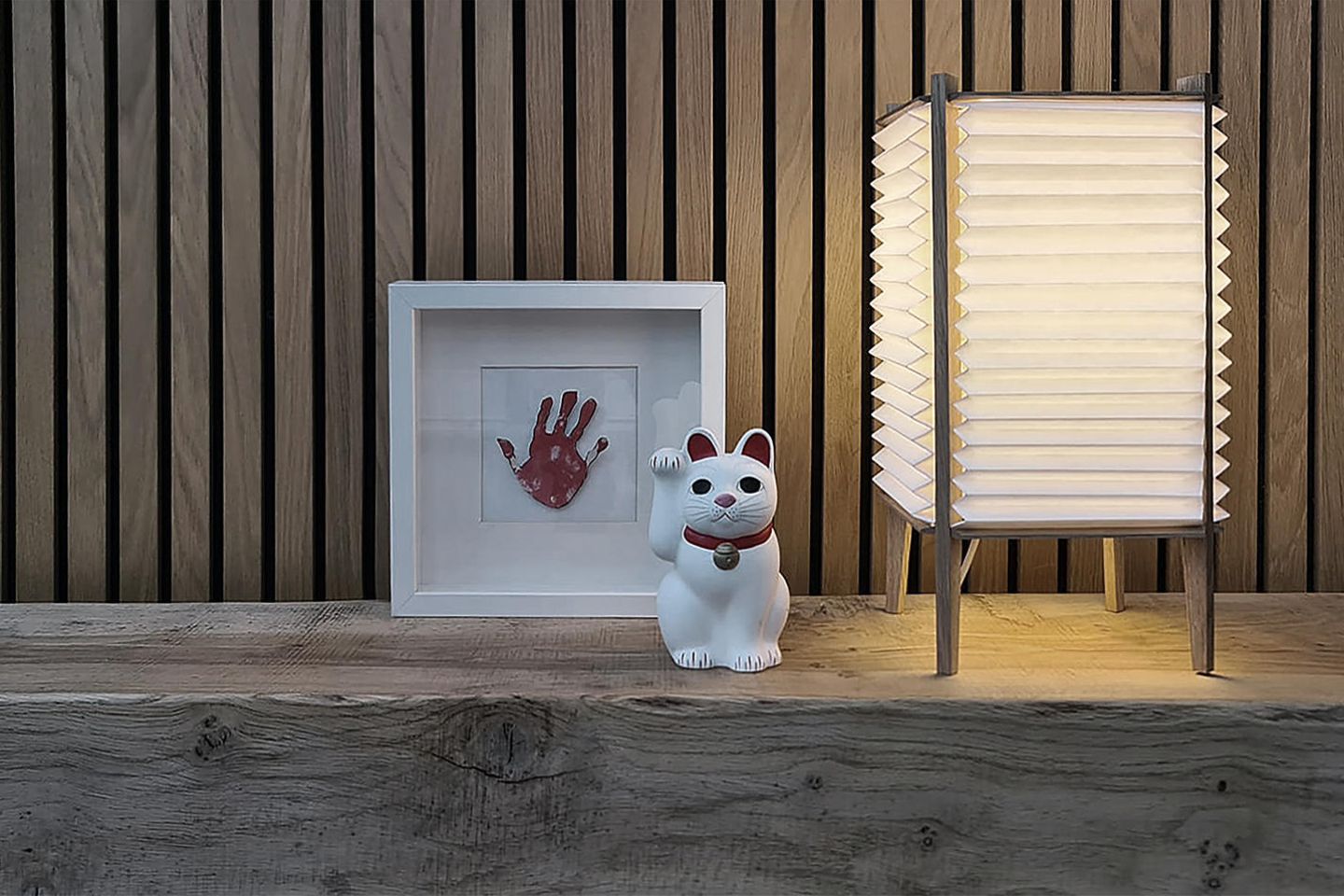 Leuchte mit gefaltetem Papierschirm neben Manekineko Katze