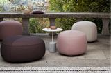 Poufs und Sitzkissen in verschiedenen Farben und Größen unter einem Torbogen auf einer Terrasse