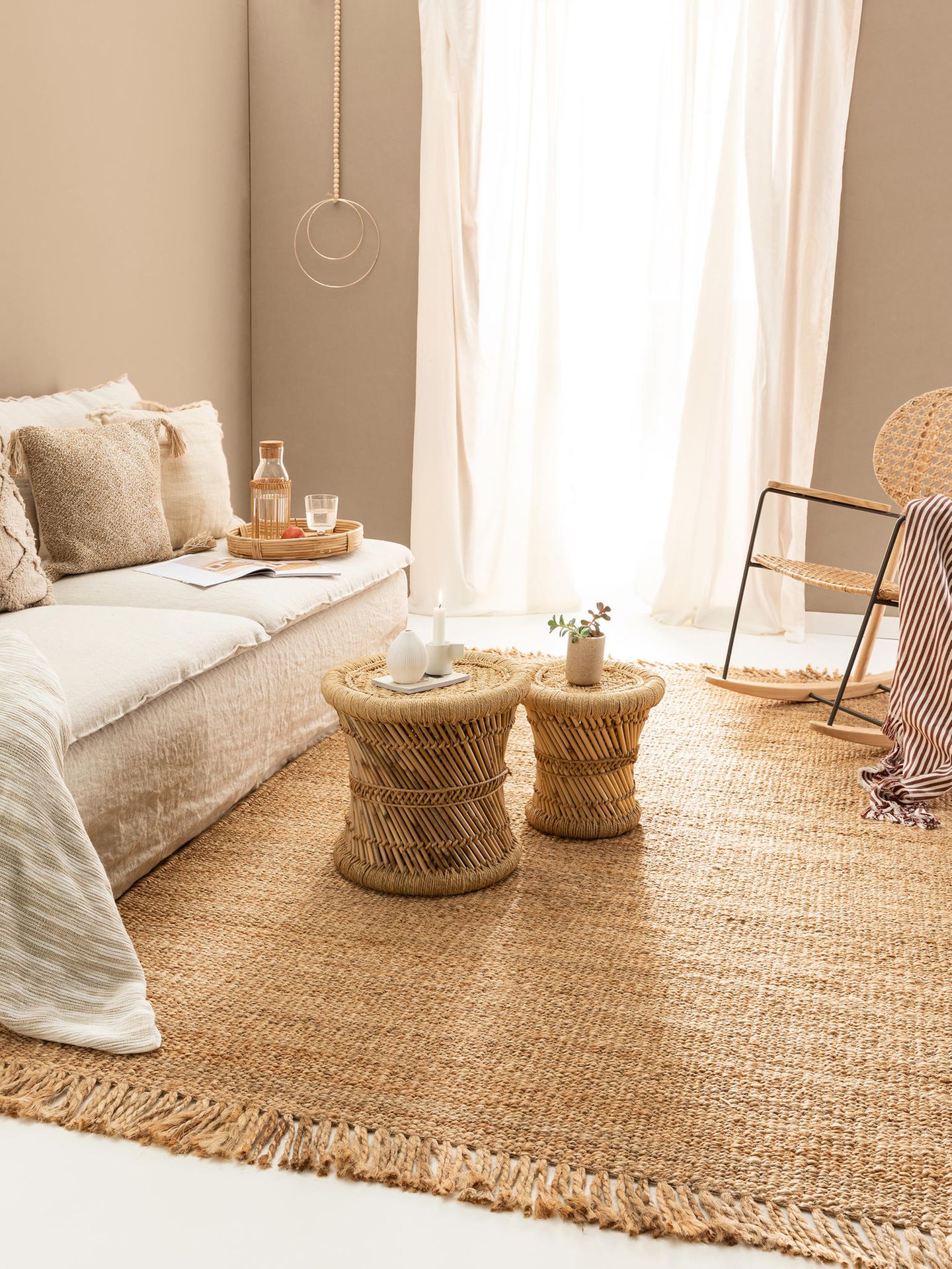 Boho-Wohnzimmer mit weißem Sofa hellen Textilien, Teppich und Beistelltischen aus Bast