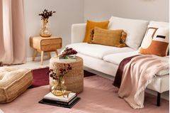 Boho-Wohnzimmer mit roten und rosa Accessoires, weißem Sofa und Korbmöbeln