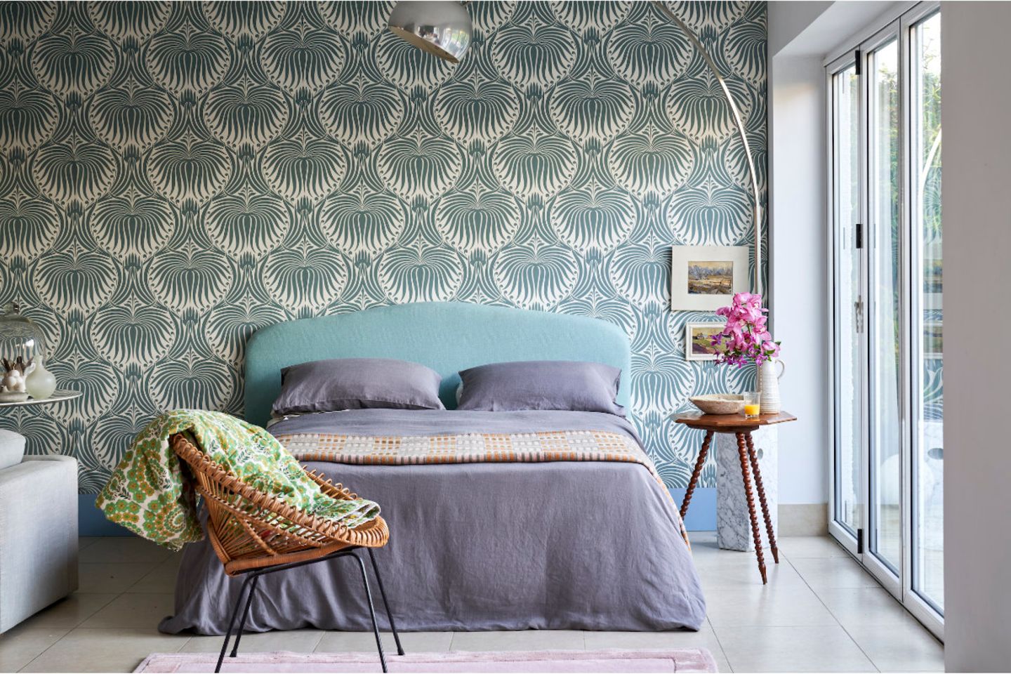 Schlafzimmer mit Muster-Tapete am Kopfende des Bettes