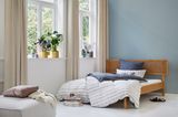 Großes Schlafzimmer mit blauer Wandfarbe und Holzbett mit Wiener Geflecht