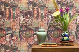 Mit Keramik, Blumen und Büchern dekorierte Kommode im Flur vor einer Tapete mit orientalischem Dekor