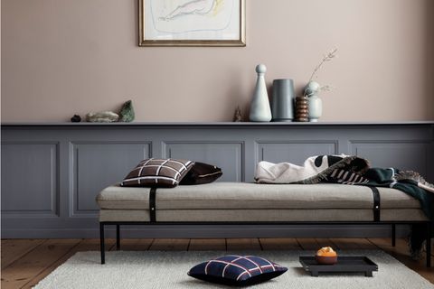 Wohnzimmer mit Daybed vor halbhoher Kassettenwand in Grau