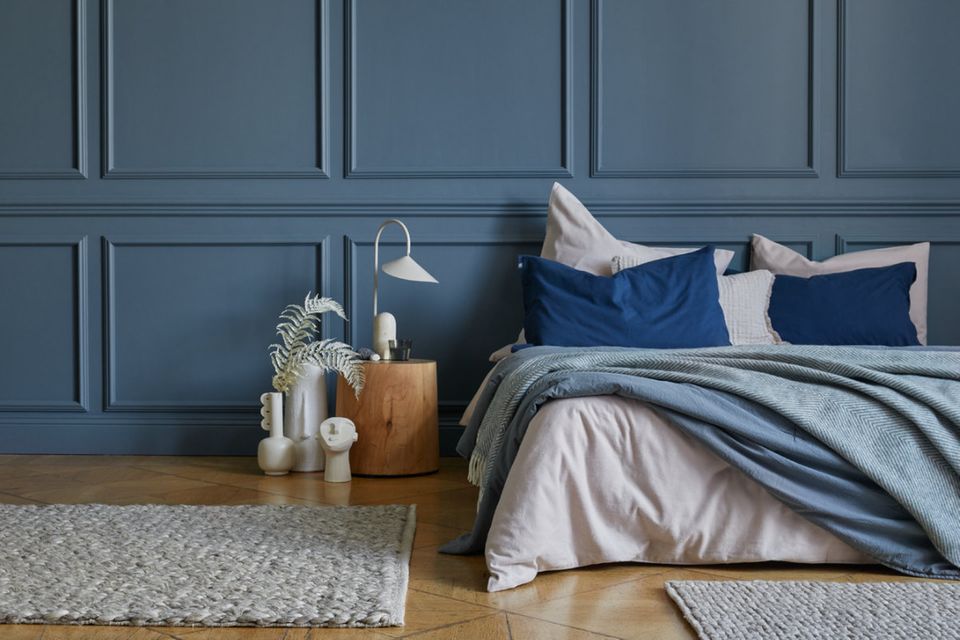 Schlafzimmer mit blauer Kassettenband und gemütlichem Bett mit vielen Kissen
