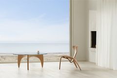 Stuhl "PK0 A" und Couchtisch "PK60" von Poul Kjærholm vor großer Fensterfront und Meer im Hintergrund