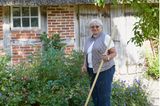 Bewohnerin Johanna Kühn mit Unkrautstecher in ihrem Garten