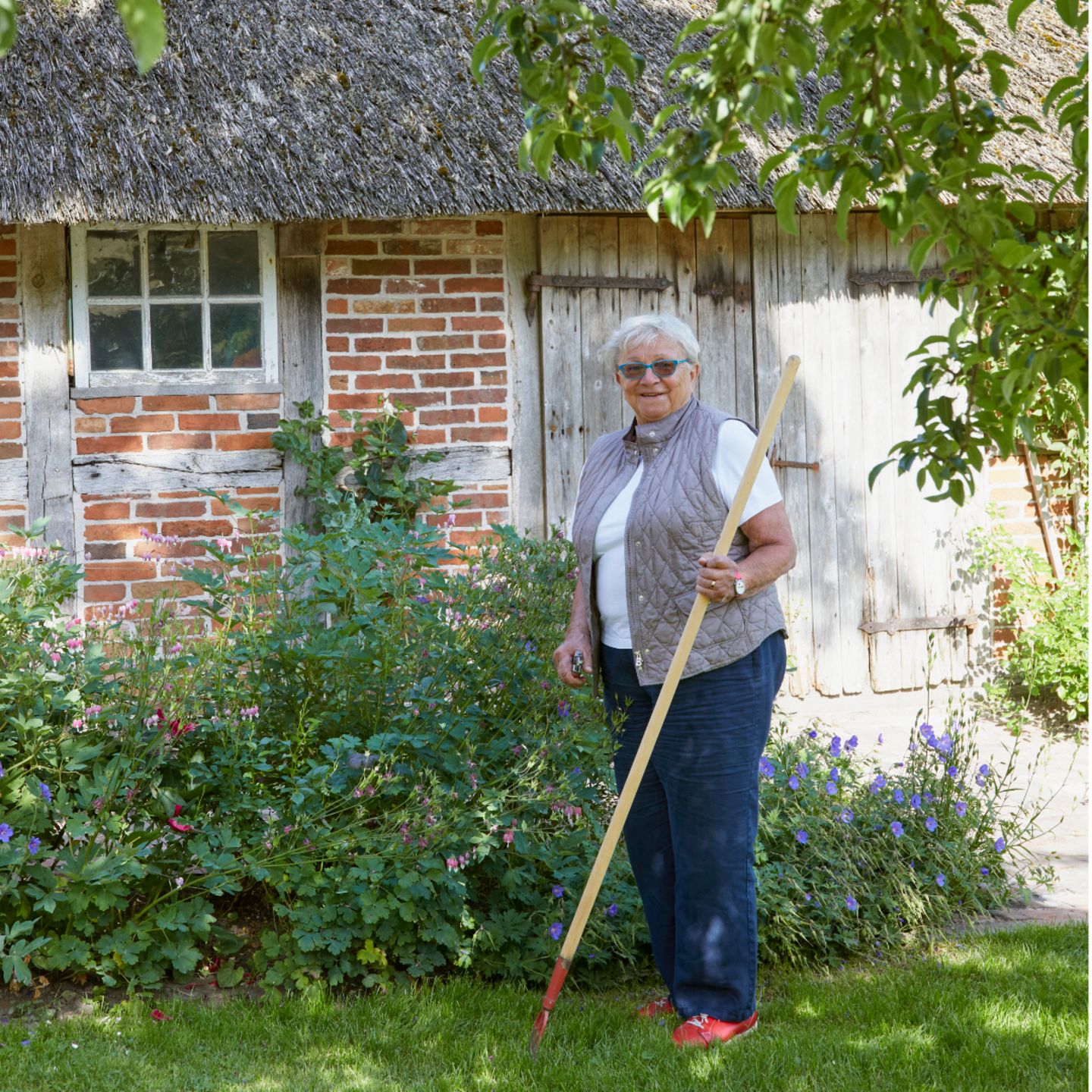Bewohnerin Johanna Kühn mit Unkrautstecher in ihrem Garten