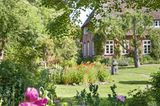 Bauerngarten mit reetgedecktem Haus im Hintergrund