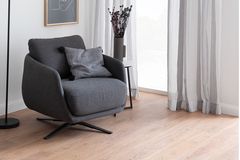 Grauer Sessel auf hellem Boden in Holzoptik