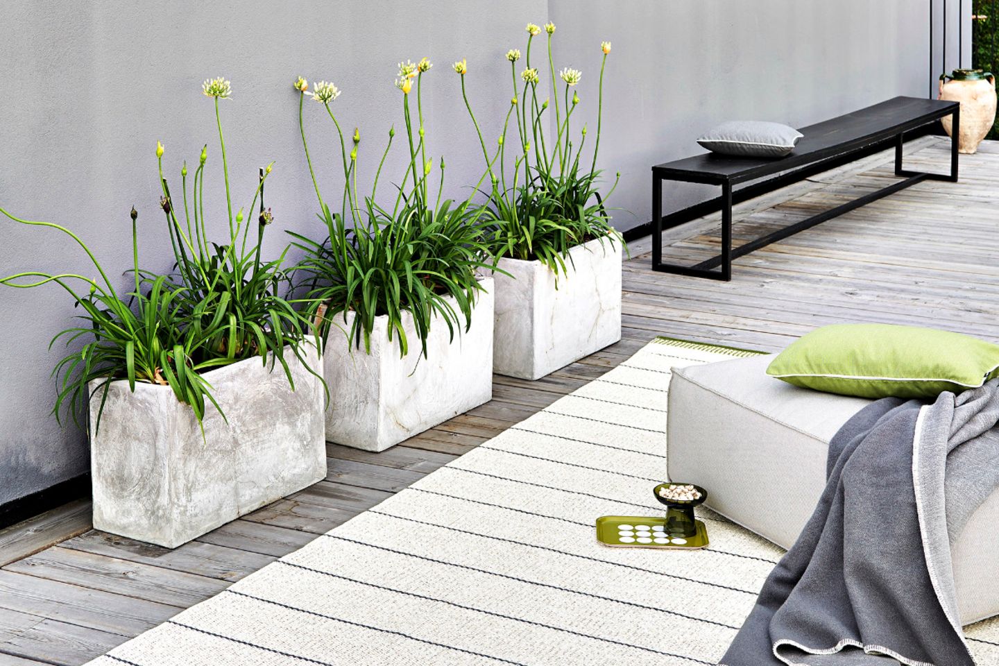 Terrasse mit drei Pflanzkübeln, Sitzbank, Outdoor-Teppich und einem Sitzkissen