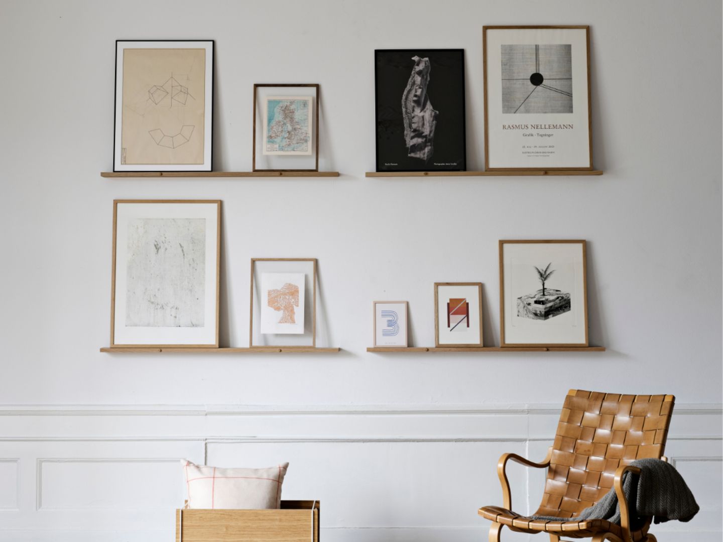 Vier Bilderleisten mit Kunstwerken an der Wand, davor Sessel
