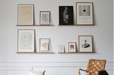 Vier Bilderleisten mit Kunstwerken an der Wand, davor Sessel