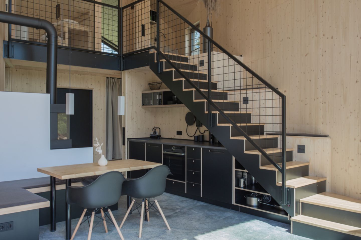 Holzverkleideter Innenraum des Ferienhauses mit schwarzer Küche und schwarzer Treppe