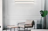 Wohnzimmer mit Sofa, Monstera und Sessel, darüber Wandleuchte