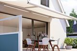 Terrasse mit ausgefahrener Markise und seitlichem Sichtschutz