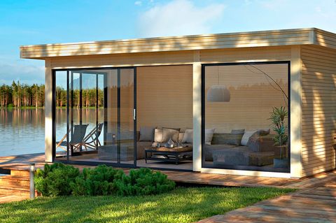 Design-Gartenhaus aus Holz mit großzügiger Fensterfront über Eck an einem sonnigen Seegrundstück