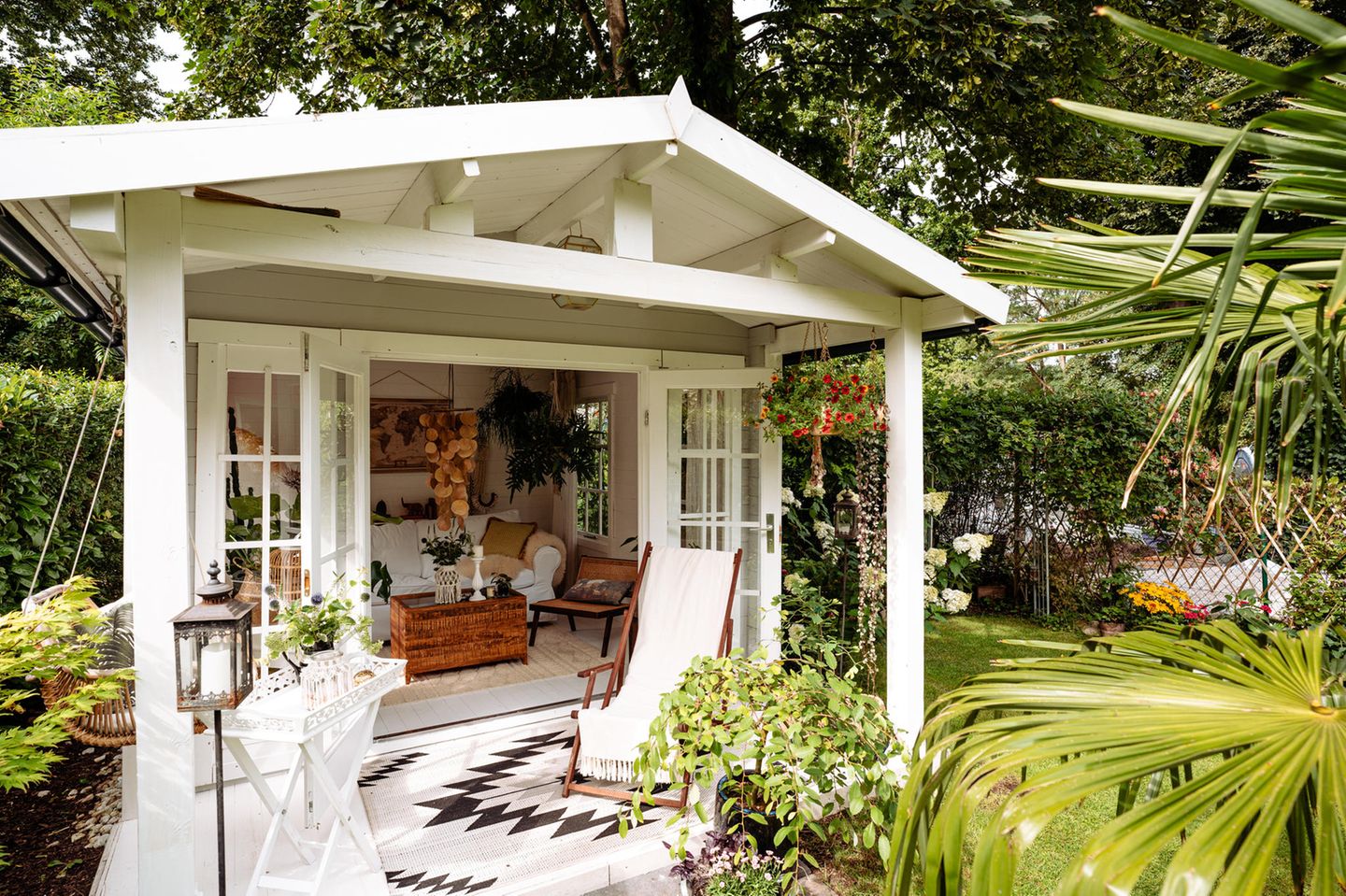 Weiß gestrichenes Gartenhaus aus Holz im Boho-Stil mit Veranda