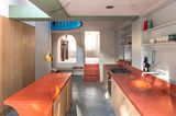 Küche mit orangenen Arbeitsplatten, langer Blickachse und Lichtschacht