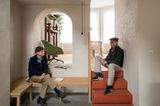 Hausherren in Leseecke vor Rundbogen und auf Treppe sitzend