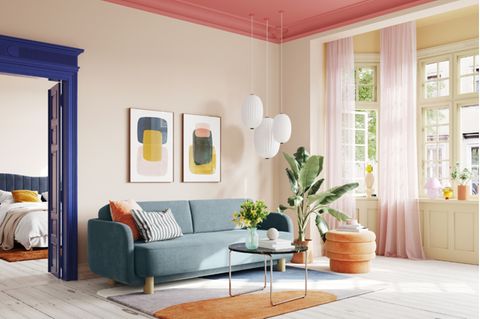 Geräumiges Wohnzimmer mit Sofa in Aquatönen, Tür in Kobaltblau und Decke in kräftigem Rosa