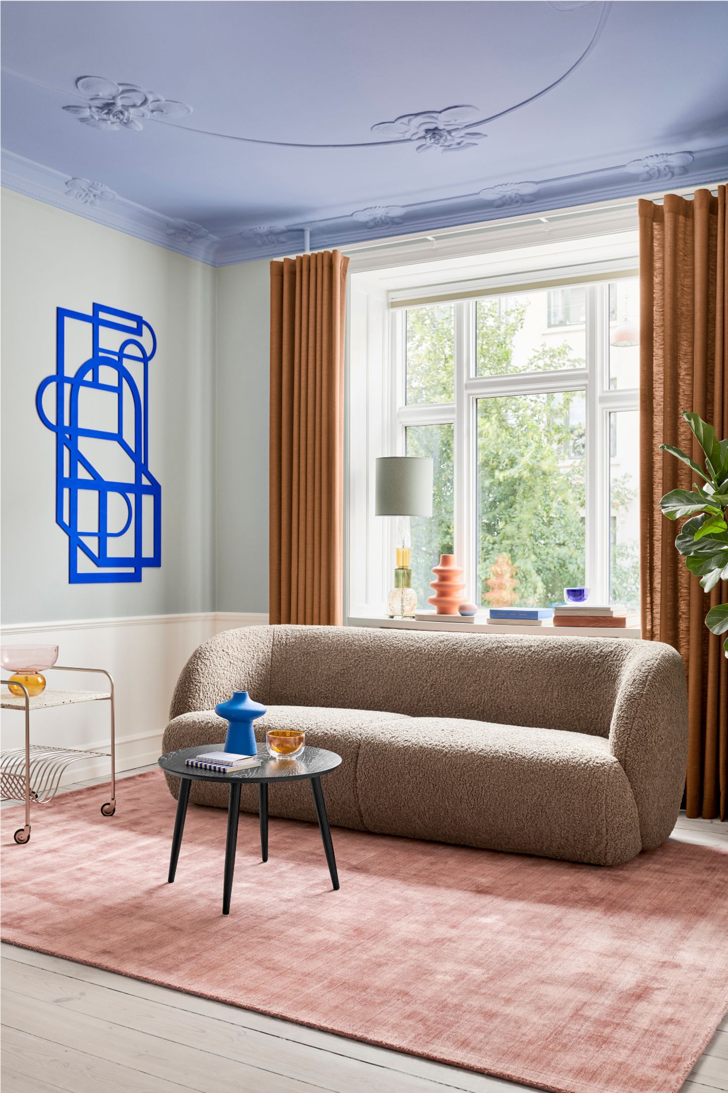 Bouclésofa in schmalem Wohnzimmer mitabstrakter  Kunst an der Wand und himmelblauer Decke