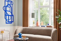 Bouclésofa in schmalem Wohnzimmer mitabstrakter  Kunst an der Wand und himmelblauer Decke