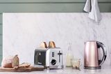 Küchenarbeitsplatte mit Toaster, Wasserkocher, einem Schneidebrett mit Brot und einer Flasche Milch