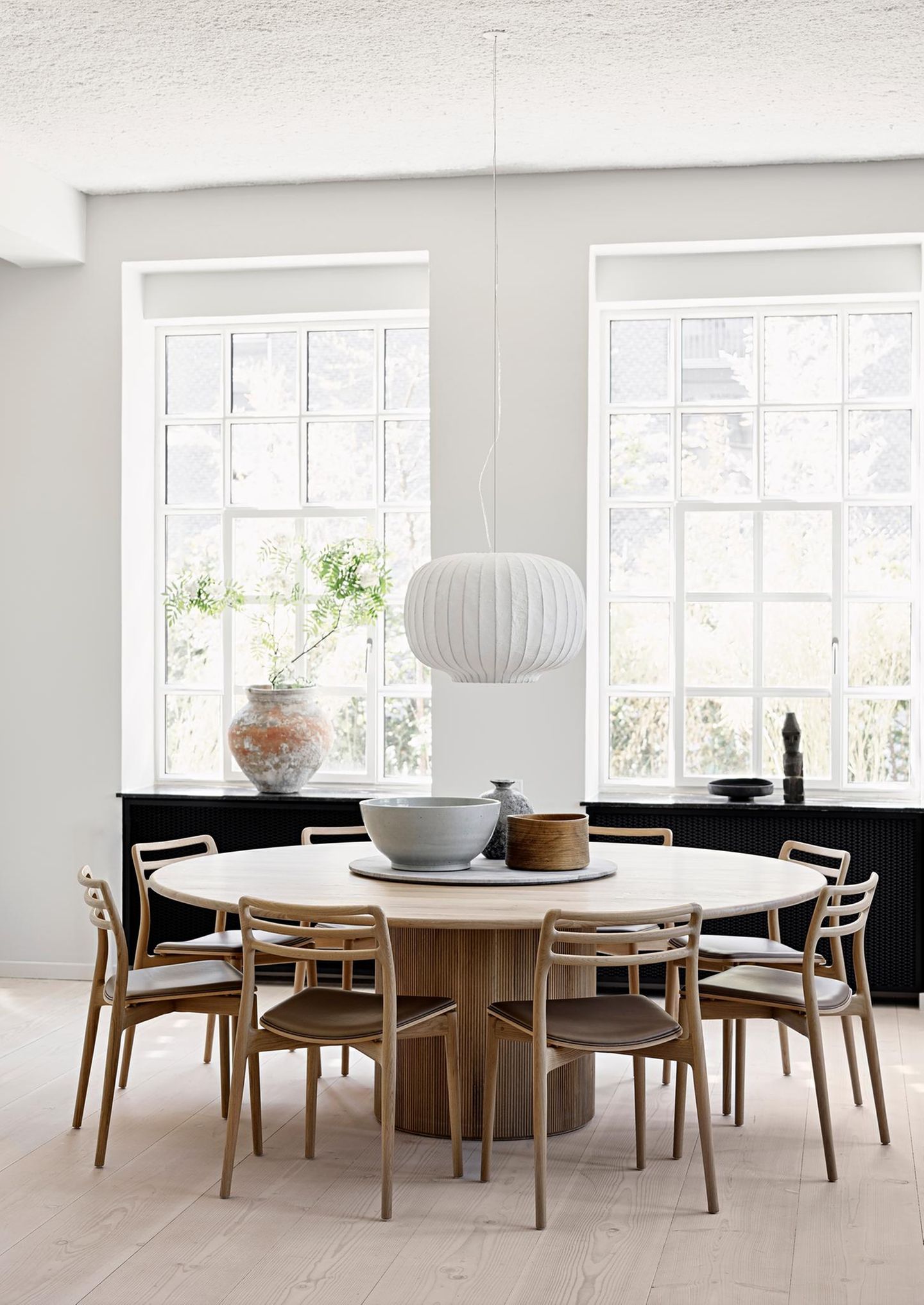 Pendelleuchte aus weißem Papier über einem Holztisch mit Altbau-Sprossenfenstern im Hintergrund