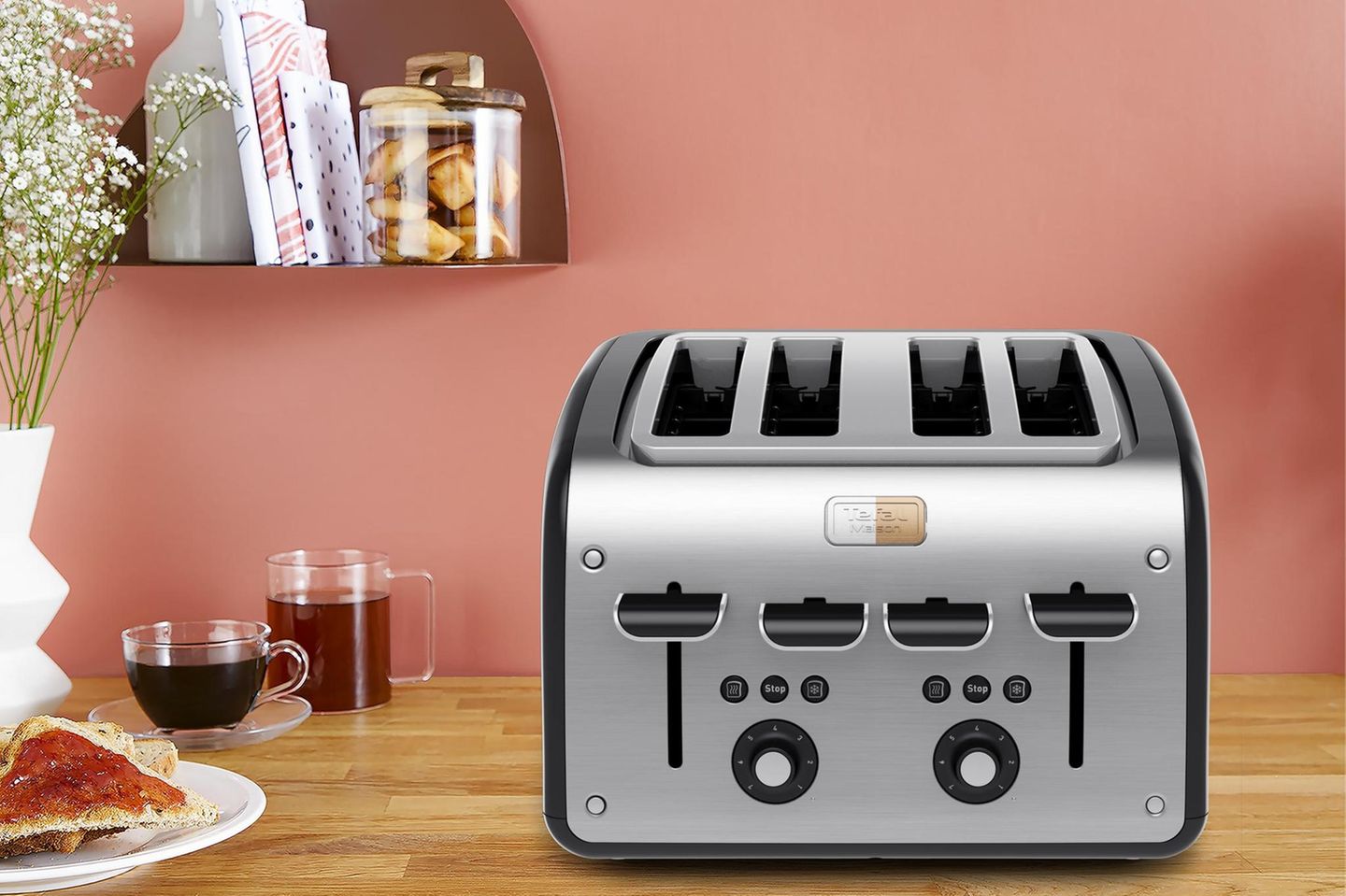 Toaster aus gebürstetem Edelstahl auf einem hölzernen Küchentisch vor einer apricotfarbenen Wand