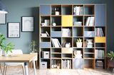 Bücherregal aus teilweise geschlossenen Kuben in taubenblau und gelb, Esstisch im Vordergrund