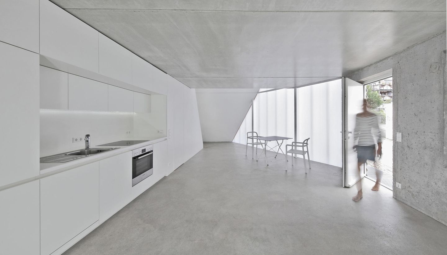 Weiße Küche im Untergeschoss mit Betonwänden und -Decke