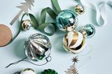 Silberne, eisblaue und gold-weiß gestreifte Weihnachtskugeln sowie silberne Baumanhänger auf eisblauem Hintergrund