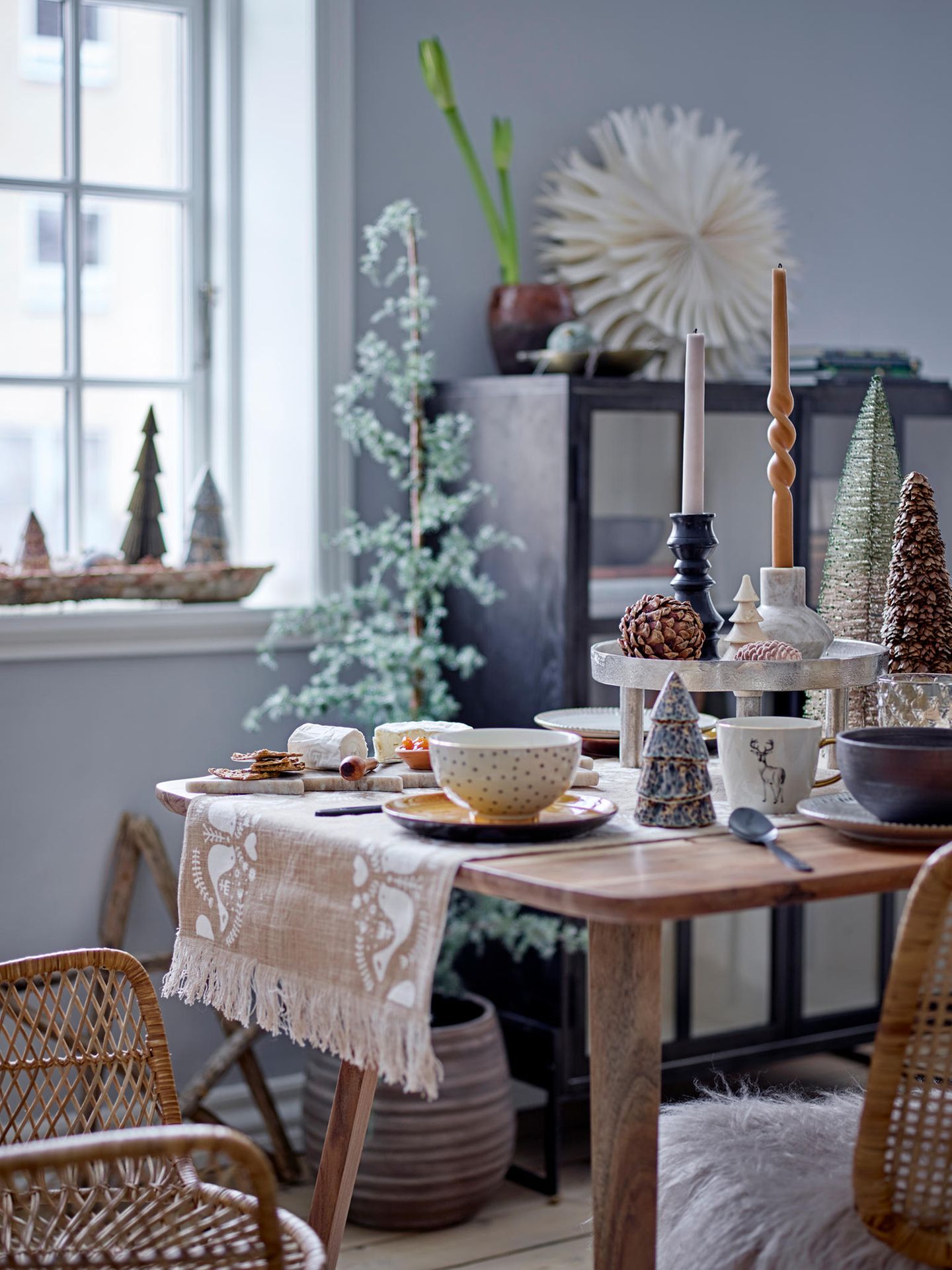 Weihnachtlich dekorierter Tisch mit Tischläufer und Etagere sowie Kerzen und Weihnachtsfiguren