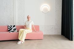 Designerin auf rosa Sofa mit Wandleuchte im Hintergrund