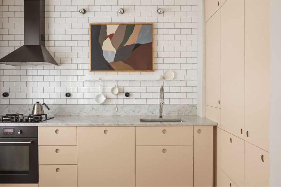 Küche in Vanillegelb mit Marmorarbeitsplatte und Küchenwand mit weißen Metro-Fliesen