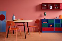 Bunte Küchenregale und Wandfarbe in blassem Rot mit rundem Esstisch und orangenen Stühlen