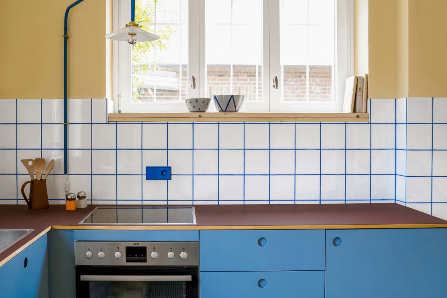 Küchenzeile mit blauen Fronten, gelber Wandfabre und Küchenspiegel in