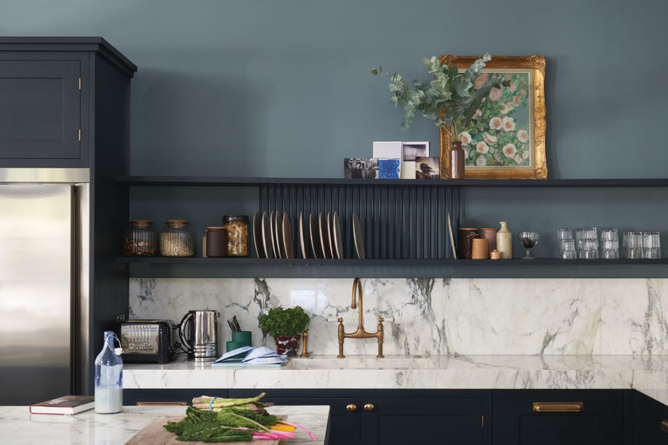 Küche mit schwarzen Fronten und Regalen, taubenblauer Wandfarbe und weißer Marmor-Arbeitsplatte