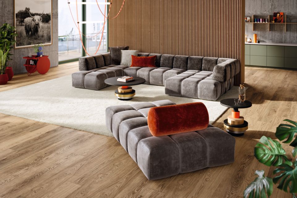 Graues Sofa mit Quaderoptik steht in einem Raum mit Holzboden