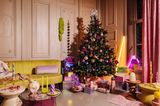 Glamouröse Weihnachtsdeko mit einem Weihnachtsbaum und Geschenken vor einer Wandvertäfelung
