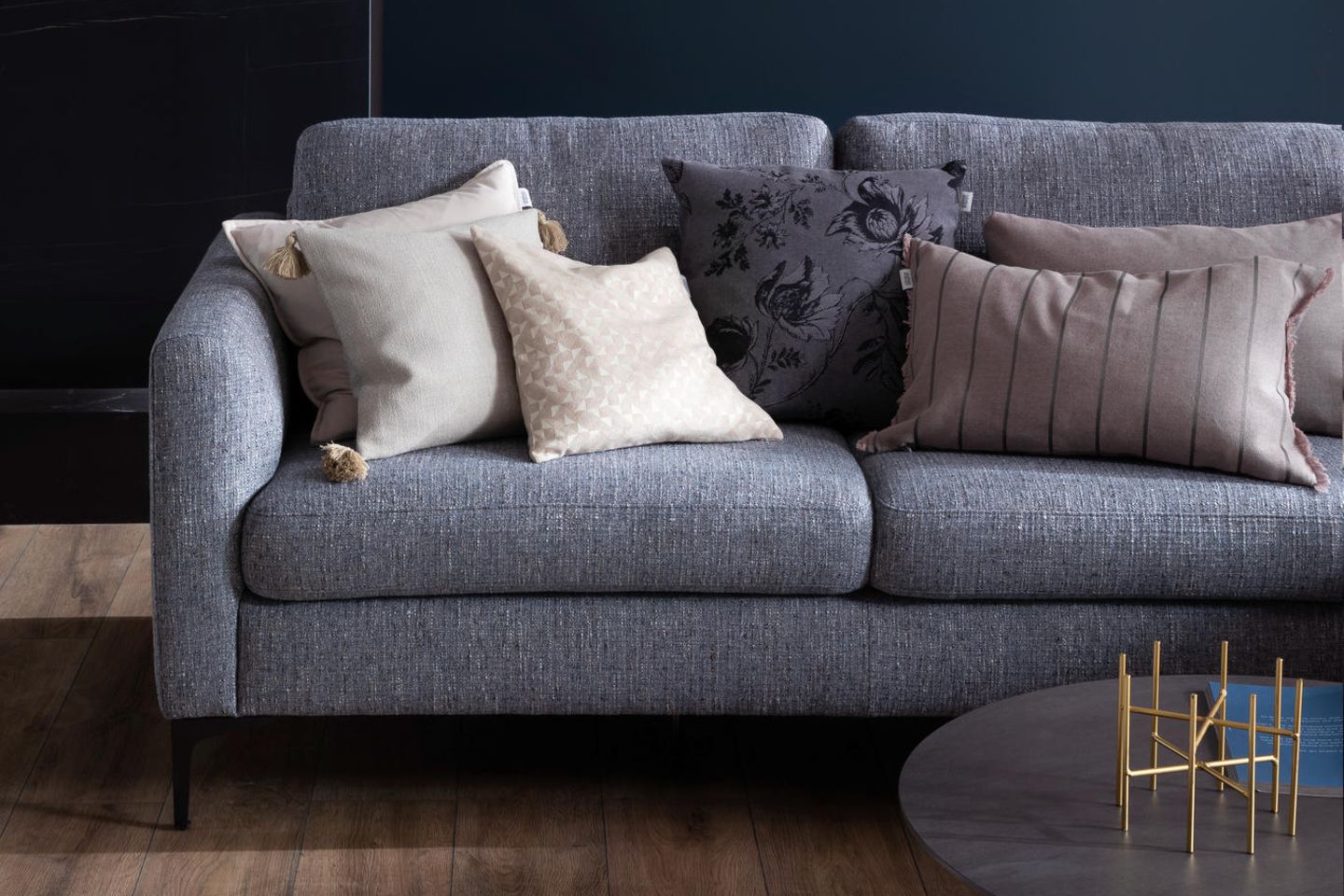 Graues Sofa mit Kissen vor blauer Wand