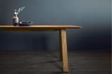 Zarte Pendelleuchte von next 125 als Strich über einem Holztisch mit minimalistischer Deko