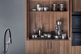 Küchenschrank aus Nussbaumfurnier hinter einer Arbeitsplatte aus kalt gewalztem Stahl