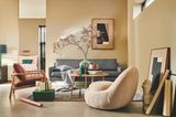 Gemütliches Wohnzimmer in Creme und Sandtönen mit einem gestreiften Sofa, Holztisch, Beerenzweig in einer Vase und Geschenken