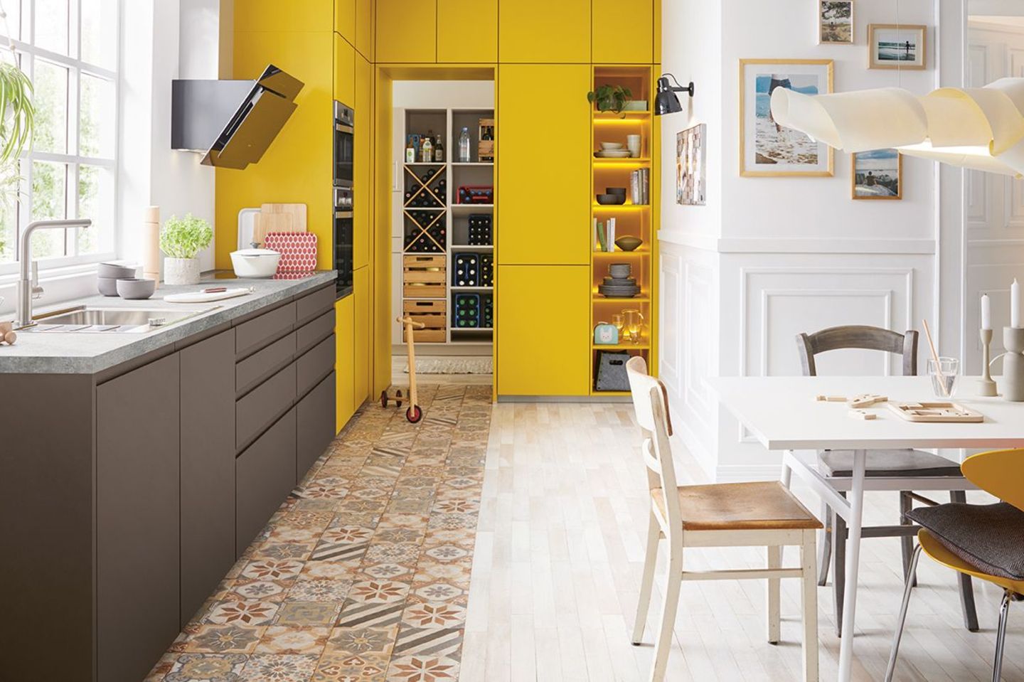 Küche mit Fronten in Dunkelgrau und Gelb mit einem Hauswirtschaftsraum und gemusterten Bodenfliesen