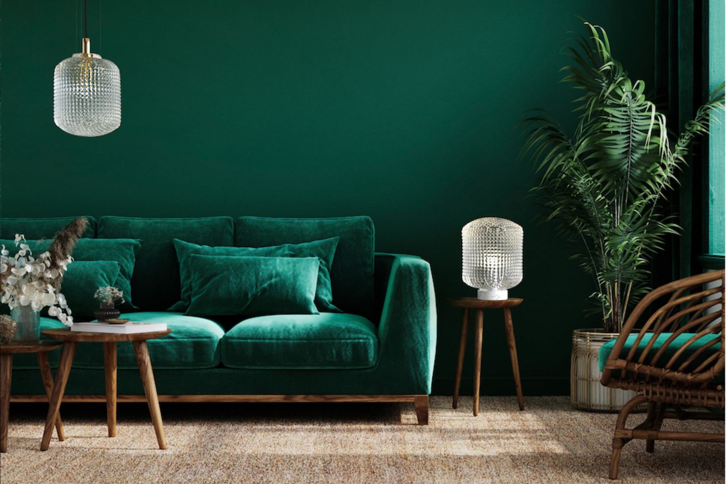 Dunkelgrün gestrichenes Wohnzimmer mit samtgrünem Sofa und dunklen Holzmöbeln sowie hellen Glasleuchten