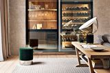 Luxuriöse Hausbar und Weinkühlschrank als Einbaumöbel in edlem Ambiente mit Samt-Pouf, Teppich und einer massiven Holzkonsole