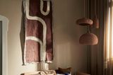 Wohnzimmer in gedeckten Ertdtönen mit drei braunen Bastkorb-Leuchten, grauem Sofa und bunten Kissen